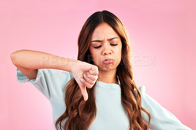 Buy stock photo Unhappy, thumb down and sad woman in a studio with an upset, moody or disappointed face. Loser, rejection and young female model posing with a disagreement hand gesture isolated by a pink background.