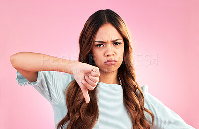 Buy stock photo Upset, thumbs down and portrait of a female in a studio with a sad, moody or disappointed face. Loser, unhappy and young woman model posing with a angry hand gesture isolated by a pink background.