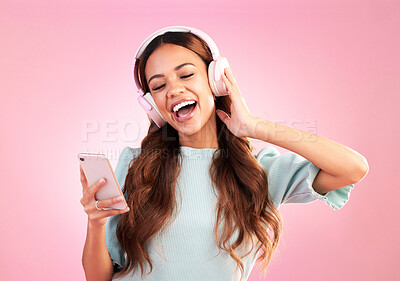 Buy stock photo Music headphones, phone and woman singing in studio isolated on a pink background. Cellphone, radio singer and happy female with mobile streaming, enjoying and listening to audio, sound or podcast.