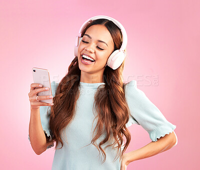 Buy stock photo Phone, music headphones and woman singing in studio isolated on a pink background. Cellphone, radio singer and happy female with mobile streaming, laughing and listening to audio, sound or podcast.