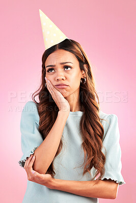 Buy stock photo Sad, birthday and hat with woman in studio for party celebration, upset and annoyed. Alone, disappointed and failure with female isolated on pink background for moody, difficulty and frustrated