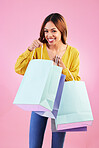 Excited woman, shopping bag and portrait in studio with a customer happy about promotion or discount. Female model or shopper on a pink background for fashion, brand and sale or surprise paper bags