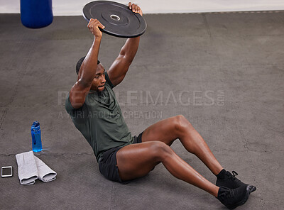 Buy stock photo Black man holding weight plate for fitness, exercise and workout in gym. Strong bodybuilder weightlifting on floor for power, energy and heavy sports challenge in training, muscle gain and balance 