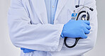 Arms crossed, closeup doctor and stethoscope in studio for medicine, medical services and wellness consulting. Healthcare worker, zoom and professional cardiology on background for heart consultation