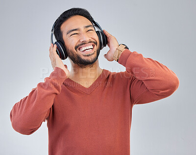 Buy stock photo Happy asian man, headphones and music in studio with streaming, audio or web subscription by background. Student guy, listening and laughing with comic podcast, standup comedy album or hip hop single