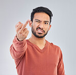 Rude, middle finger and portrait of asian man in studio for fail, conflict and problem. Annoyed, upset and aggressive with male and hand gesture on gray background for hate, disrespect and furious