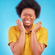 Black woman, fingers crossed and hope in studio, blue background and ...