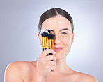 Makeup, cosmetic and portrait of a woman with brushes isolated on a studio background. Happy, beauty and model showing a brush set for cosmetics, foundation application and glamour on a backdrop