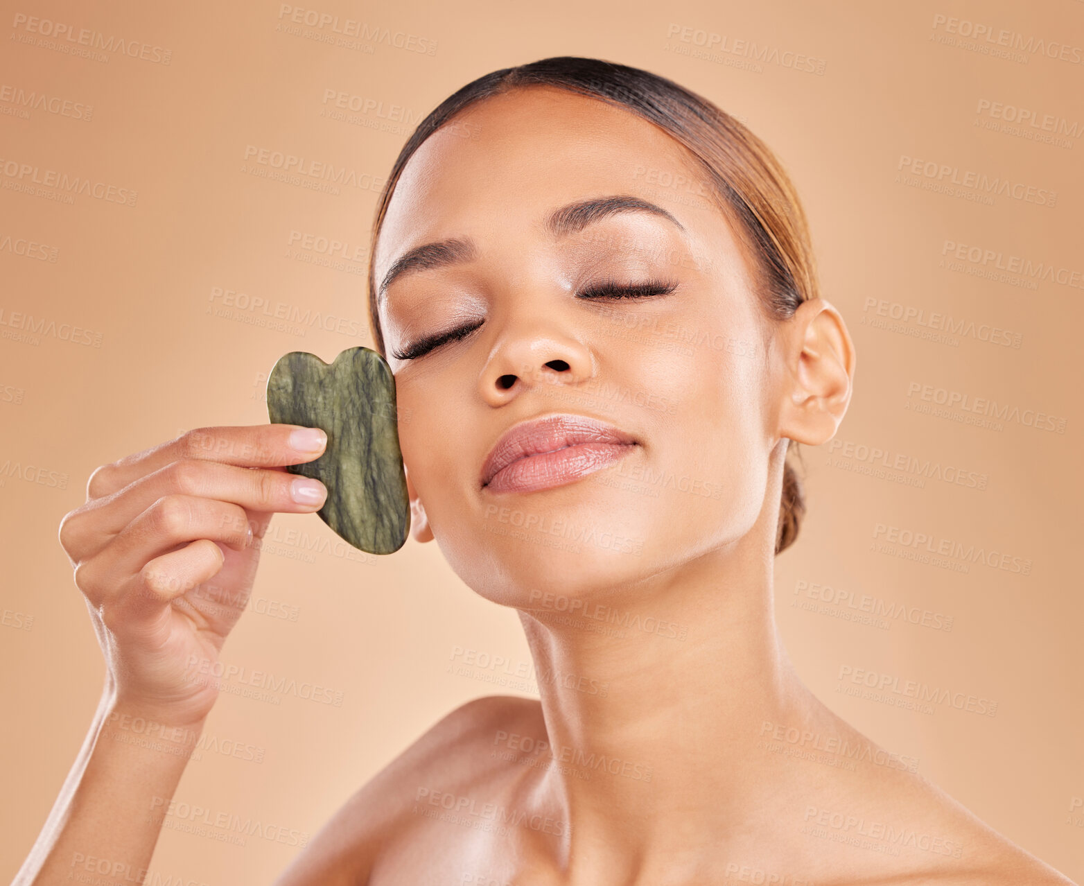 Buy stock photo Skincare, facial and massage with gua sha by woman in studio for beauty, cosmetics and facelift on brown background. Relax, face and anti aging tool for girl beauty model calm with luxury dermatology