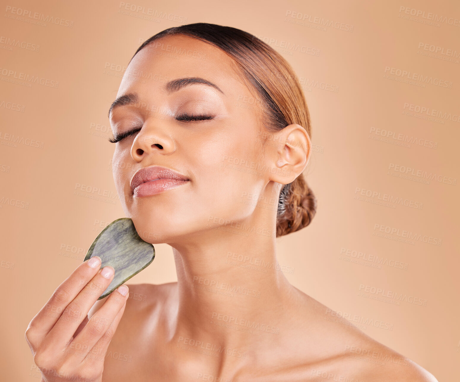 Buy stock photo Beauty, facial and massage with gua sha by woman in studio for skincare, cosmetic or facelift on brown background. Calm, face and anti aging tool for girl model relax with luxury dermatology wellness