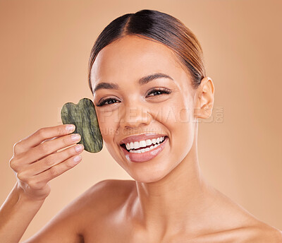 Buy stock photo Beauty, portrait and a woman with gua sha for skin glow and shine in studio on brown background. Aesthetic female model satisfied with facial massage, dermatology cosmetics and wellness for skincare

