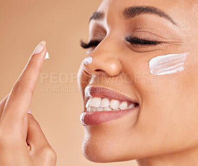 Buy stock photo Face, skincare smile and woman with cream in studio isolated on a brown background. Dermatology, beauty cosmetics and closeup of happy female model with lotion, creme or moisturizer for skin health.