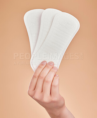 Buy stock photo Hand, sanitary pads and period with a woman in studio on a brown background for female hygiene or care. Lifestyle, and gynecology with a female holding a feminine product for her menstrual cycle