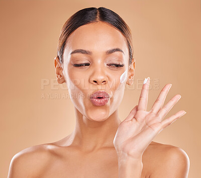 Buy stock photo Beauty, face cream and a woman in studio for skincare with dermatology, cosmetics or makeup. Happy aesthetic female model on a brown background for self care, skin glow and facial wellness lotion