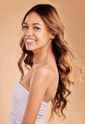 Buy stock photo Beauty, haircare and face portrait of woman with curls in studio for growth shine or strong texture. Aesthetic female with long, color and healthy hair and smile after salon care on brown background
