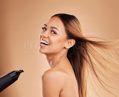 Buy stock photo Woman, beauty and hair care portrait with hairdryer and growth or shine for strong texture on brown background. Aesthetic female happy in studio with blow dryer and heat protect for health and color