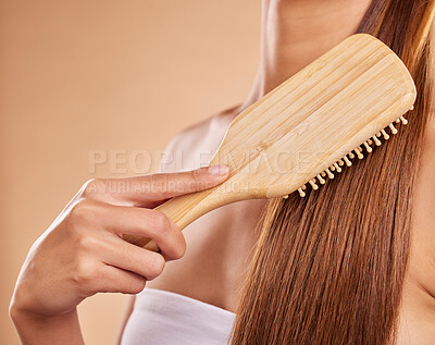 Buy stock photo Hairbrush, hair care and woman brushing her hair in a studio for wellness, health and self care. Cosmetic, beauty and closeup of a female model doing a hairstyle or combing knots by brown background.