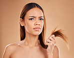 Hair care, frustrated and portrait of a woman with split ends isolated on a studio background. Unhappy, frizzy and a girl with a problem with damaged, tangled and breakage of a hairstyle on backdrop