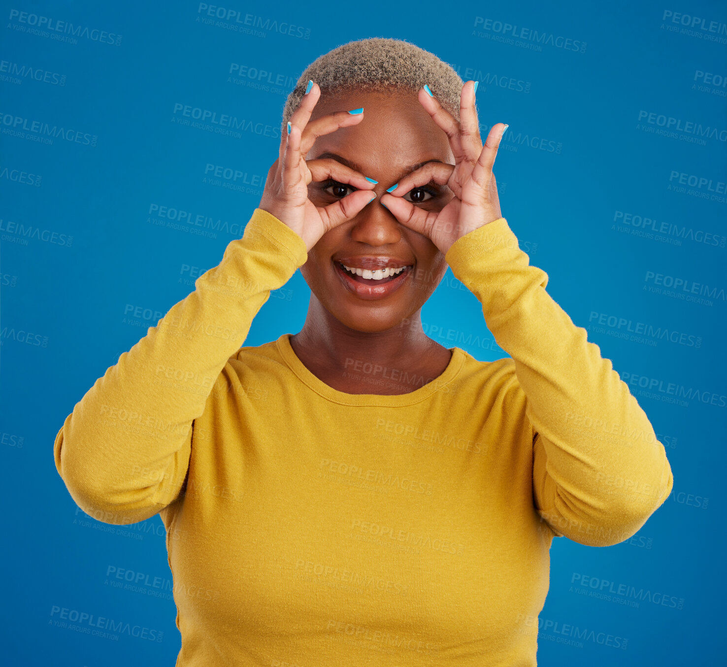 Buy stock photo Black woman, binocular hands and eyes in studio portrait for comic funny face with smile, fashion and happy. Student girl, model and ok hand gesture with happiness, youth and pride by blue background