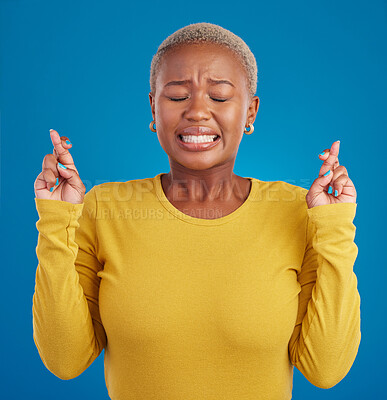 Buy stock photo Nervous, fear and fingers crossed by desperate black woman isolated against a studio blue background. Hope, luck and wishing young female doing wish hand gesture worried, miracle and worried
