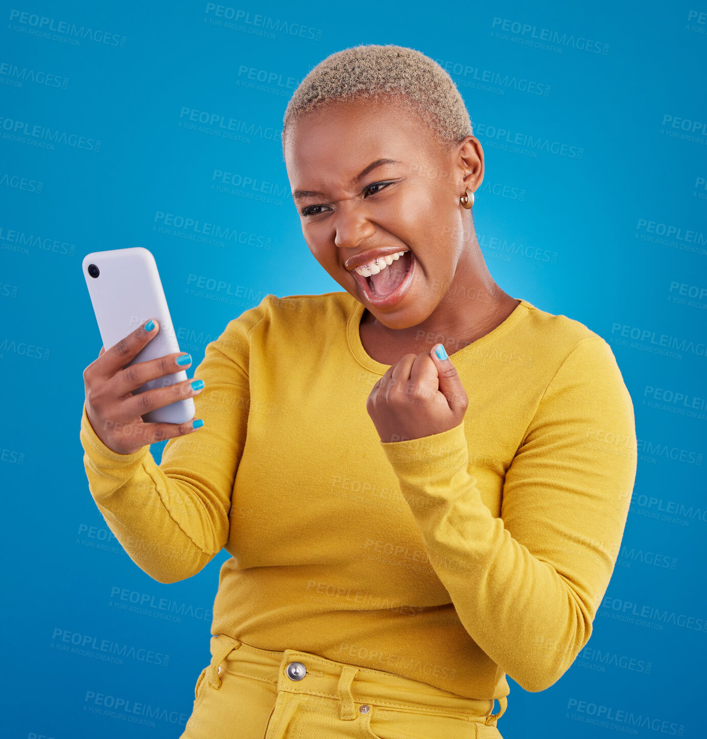 Buy stock photo Black woman, phone and fist celebration in studio, blue background and winning online prize. Happy female model celebrate mobile promotion, bonus and excited for deal, success and competition winner