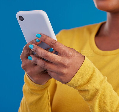 Buy stock photo Phone, typing and closeup of hands of woman in studio for social media, text message and browse website. Communication, technology and girl on internet, network and chat online on blue background