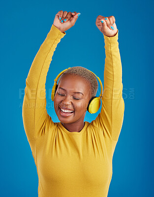 Buy stock photo Black woman with headphones, dance and listening to music with rhythm and fun with freedom on blue background. Happy female with arms raised, streaming radio with dancing and carefree in studio