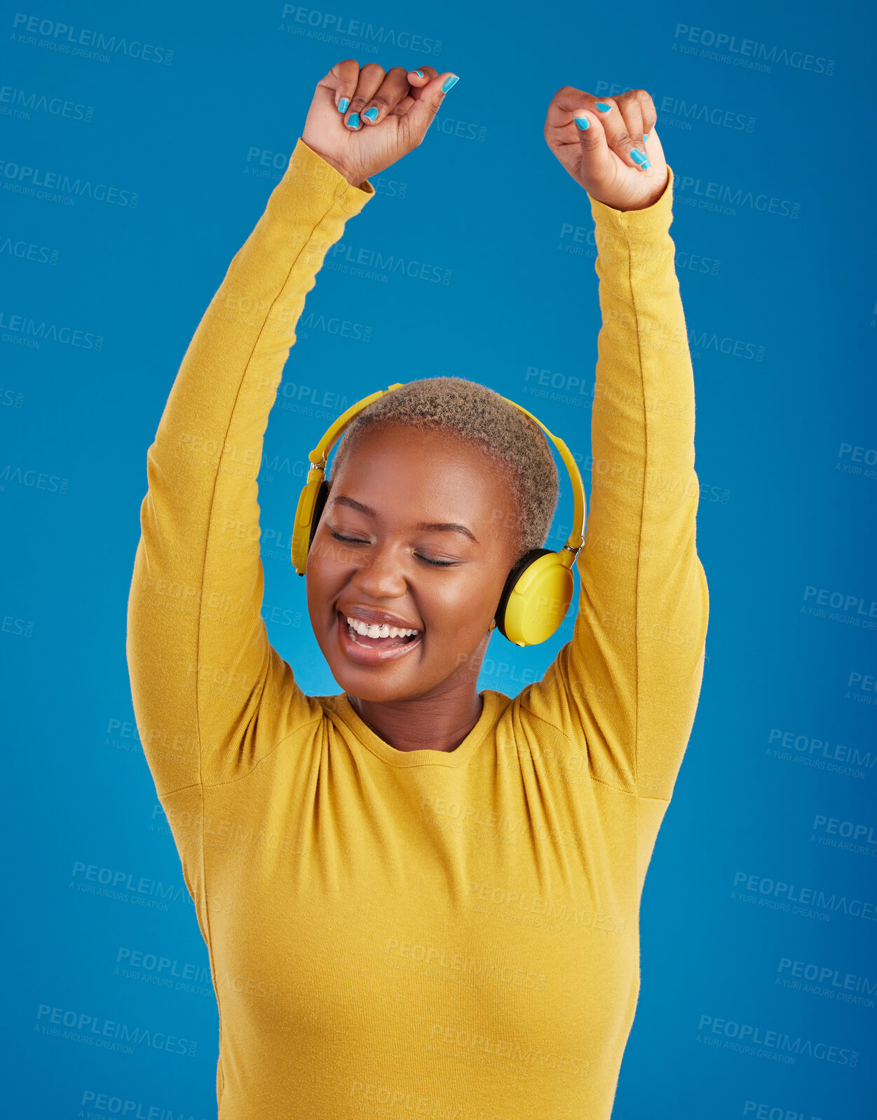 Buy stock photo Black woman with headphones, dance and listening to music with rhythm and fun with freedom on blue background. Happy female with arms raised, streaming radio with dancing and carefree in studio