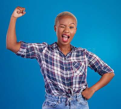 Buy stock photo Wink, arm flex and portrait of black woman in studio for empowerment, confident and success. Achievement, hard work and pride with female isolated on blue background for power, strong or motivation