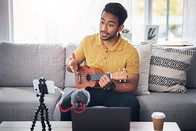 Buy stock photo Podcast, guitar and phone with a man online to talk and coach during live streaming lesson. Asian male person talking on home sofa with a ukulele as content creator teaching music on education blog