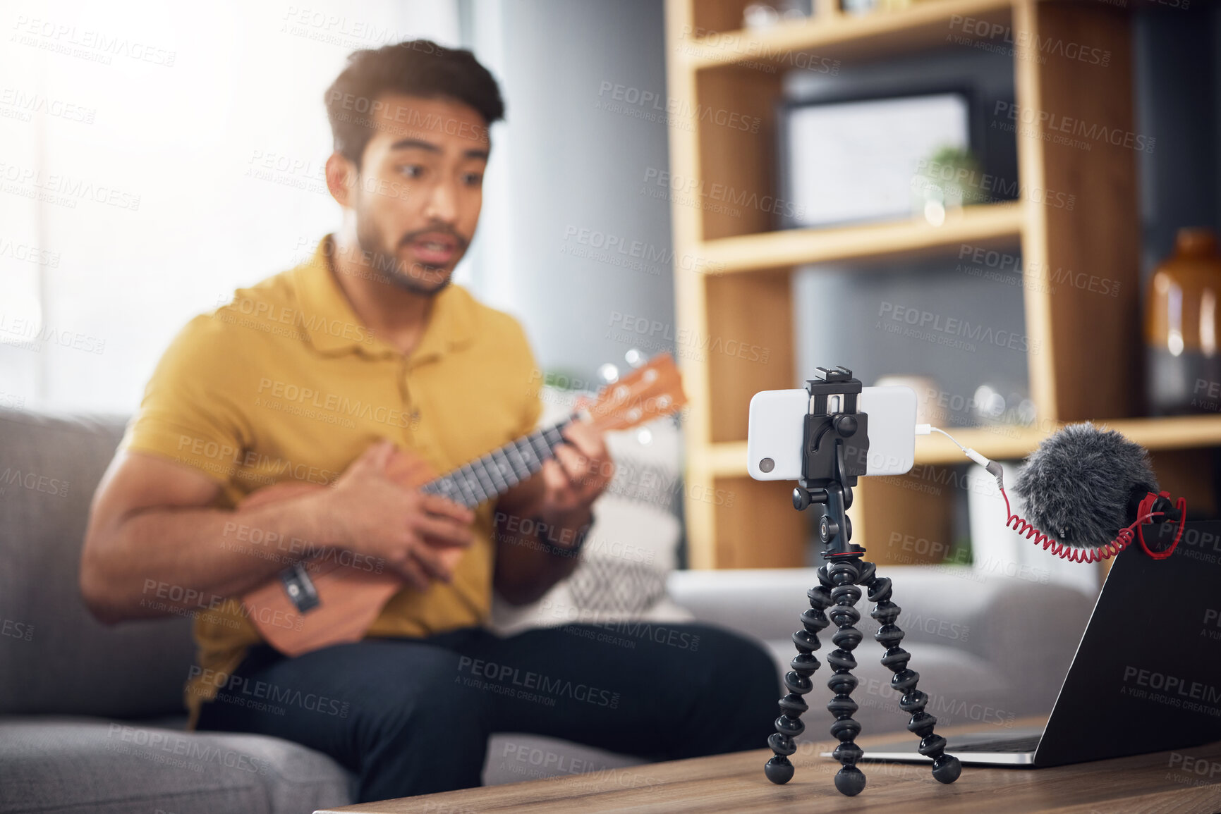 Buy stock photo Podcast microphone, phone and guitar with a man online to coach during live streaming lesson. Asian male influencer on home sofa with a ukulele as content creator teaching music on education blog