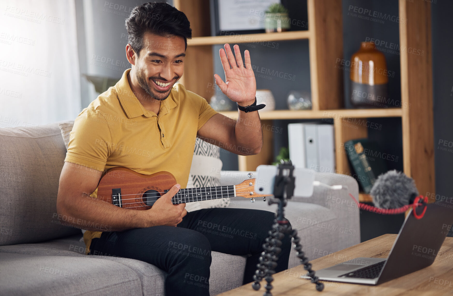 Buy stock photo Podcast, guitar and laptop with a man online to wave and coach during live streaming lesson. Asian male person happy on home sofa with a ukulele as content creator teaching music on education blog