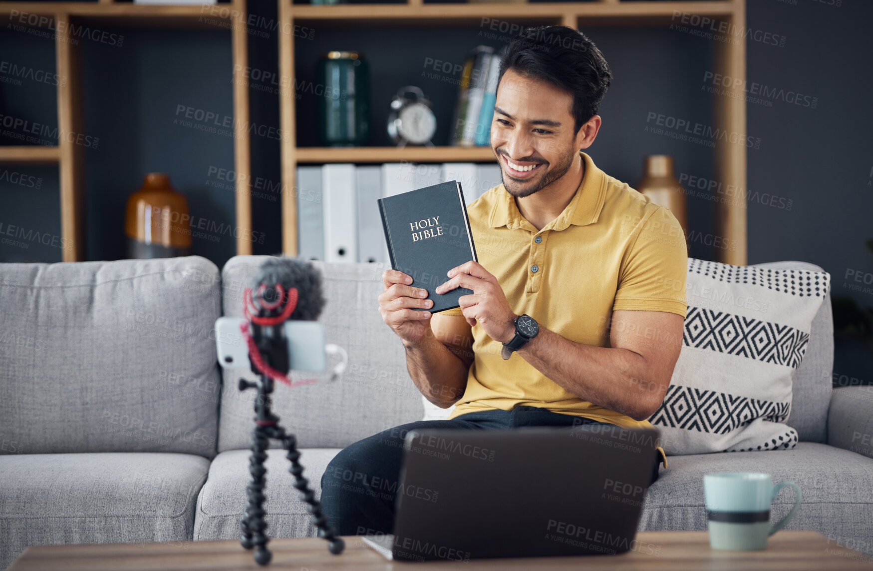 Buy stock photo Bible, smile and man study with phone and microphone online live streaming. Asian male on home sofa with Christian religion book as blog or podcast content creator or influencer teaching or studying 