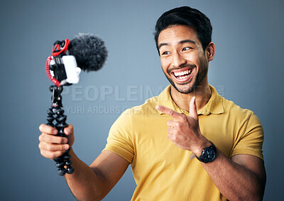 Buy stock photo Phone, content creation and Indian man in studio with smile, webinar recording and live streaming on grey background. Internet, webcam and happy online influencer with smile on social media channel.