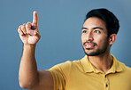 Finger, pointing and asian man in studio with hand gesture, sign or showing mockup on blue background. Smile, point and male with idea on space for advertising, product placement and isolated
