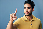 Pointing, finger and happy man in studio with hand gesture, sign or showing mockup on blue background. Smile, point and asian male with idea on space for advertising, product placement and isolated