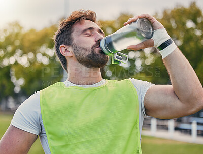 Buy stock photo Drinking water, fitness and hydration with a sports man outdoor for a competitive game or event. Exercise, training and health with a male athlete taking a drink from a bottle during a break or rest
