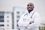 African, man and doctor in city for portrait, arms crossed and smile for wellness, healthcare and mockup. Young black medic, confidence and happy in metro with blurred background for mock up space