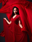 Woman, art and fashion, fabric veil on dark background with beauty and aesthetic movement. Flowing silk motion, fantasy and artistic portrait of happy model with smile in red designer dress in studio