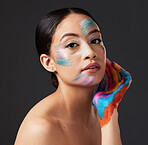 Woman, portrait and beauty with rainbow makeup art on hand and face in studio. Creative skin and facial cosmetics on female aesthetic model on gray background for lgbtq color inspiration on hands