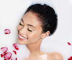 Beauty, milk and rose petals with woman in bath for spa treatment, relax and skincare. Wellness, cosmetics and pampering with female and flowers from top view for grooming, satisfaction and self care
