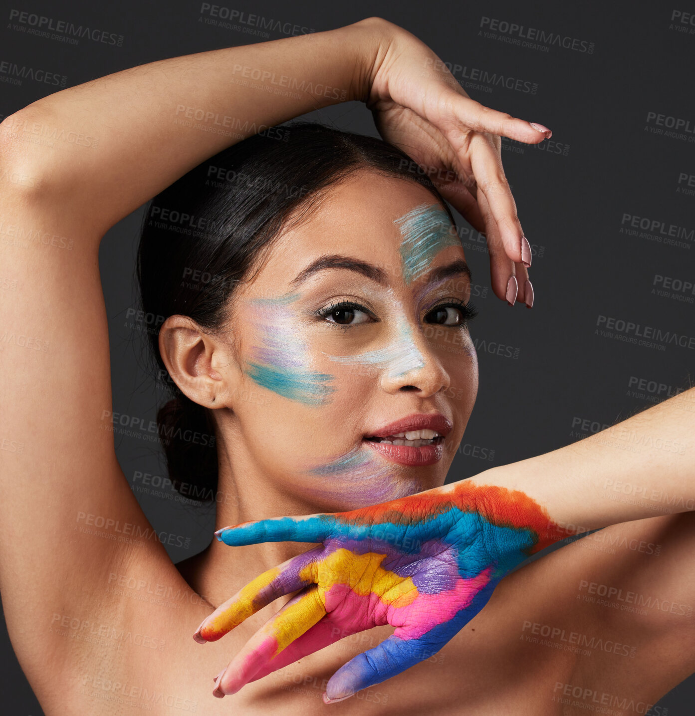 Buy stock photo Woman, portrait and beauty with rainbow paint art on hand and face in studio with a smile. Creative skin and makeup on female aesthetic model on gray background for lgbtq color inspiration on hands