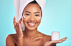 Skincare, beauty and portrait of black woman with cream, towel and smile in bathroom routine or skin glow on blue background. Cosmetics, facial and African model with lotion product in hand in studio