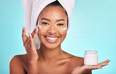 Buy stock photo Skincare, beauty and portrait of black woman with cream, towel and smile in bathroom routine or skin glow on blue background. Cosmetics, facial and African model with lotion product in hand in studio