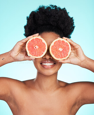 Buy stock photo Black woman, face and hands with grapefruit for skincare nutrition, beauty or vitamin C against a blue studio background. Portrait of African female smiling with fruit for natural health and wellness