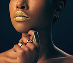 Closeup, jewelry and black woman with foundation, makeup and grooming against dark studio background. Zoom, female and lady with gold lipstick, rings and cosmetics for skincare, aesthetic and luxury