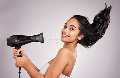 Buy stock photo Portrait, blow dry and hair with a model woman in studio on a gray background holding an appliance. Salon, smile and hairdryer with an attractive young female drying her hairstyle for beauty