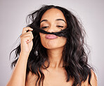 Beauty, salon and woman smell hair, aesthetic and cosmetics on a grey studio background. Female, moustache and lady with facial expression, silly and goofy with treatment, smelling clean and wellness