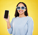 Phone, fashion and portrait of woman with sunglasses in yellow studio for social media, website and internet. Communication, mockup space and happy girl on  smartphone for chat, promotion and network