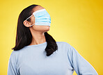 Covid, face mask and blindfold with woman in studio for medical,  crazy and healthcare. Comic, virus and carefree with female on yellow background for vaccine, protection and pandemic safety